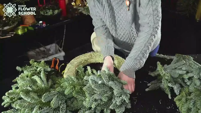Hands wrapping reel wire around a layer of fir on the hay ring