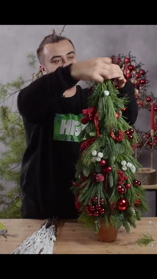 The maker wrapping the narrow point of the decorated tree