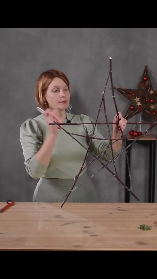 The maker holding the bare twig star with additional branches inside its points