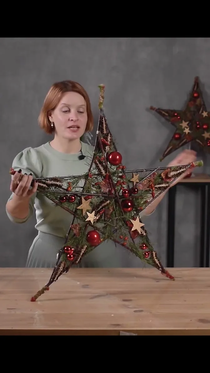 A finished twig star with pine greenery, red baubles and small wooden stars