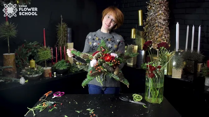 A finished star-shaped bouquet with red flowers, pink carnations, orange rose hips and fir-covered twig points.