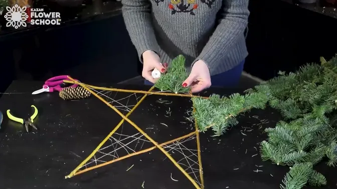 Short fir sprigs being wired onto one point while the center of the star remains open.