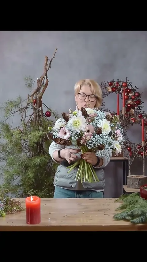 A broad winter bouquet filled with pale flowers and blue gypsophila, with individual cones extending around the edge.