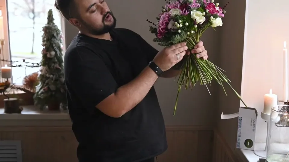Fir added beneath the outside flowers while the bouquet is tilted to reveal its lower edge and stem bundle.