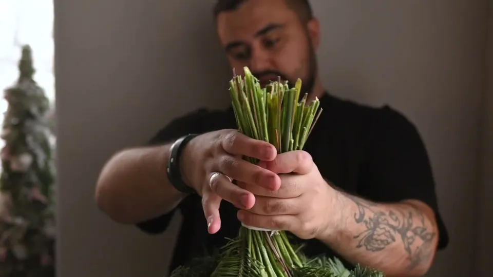 The tied bouquet held upside down, with the stem ends gathered together above the fir collar.