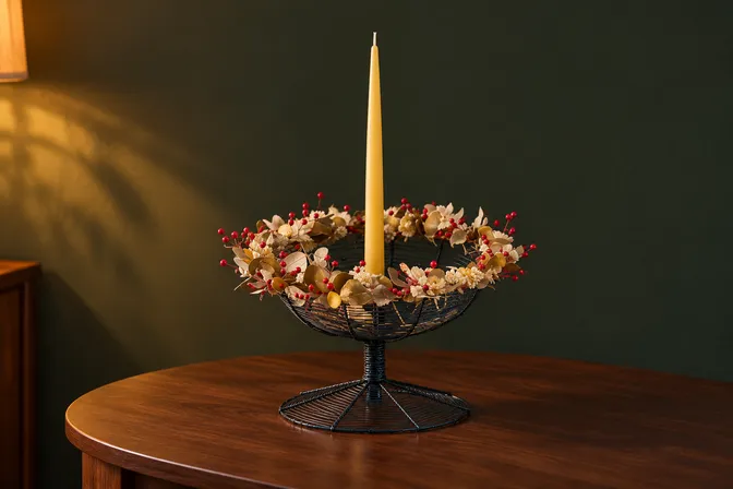 A woven bowl edged with dried flowers and a tall candle