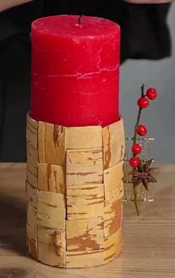 Red decorative candle extended with a birch-bark base and a fine gold wire detail with red berries.