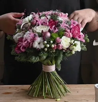 Round winter bouquet with pink and white flowers, cotton, baubles and a collar of fir.