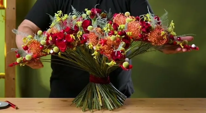 Wide festive bouquet with red and orange flowers on an open two-tier star frame.