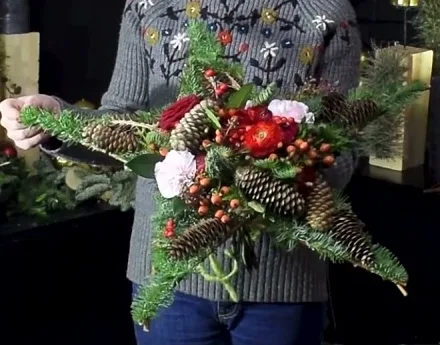 Five-pointed evergreen twig-star bouquet with red and pale flowers, berries and pinecones.