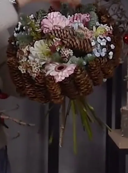 Pink and white flowers in a pinecone collar.