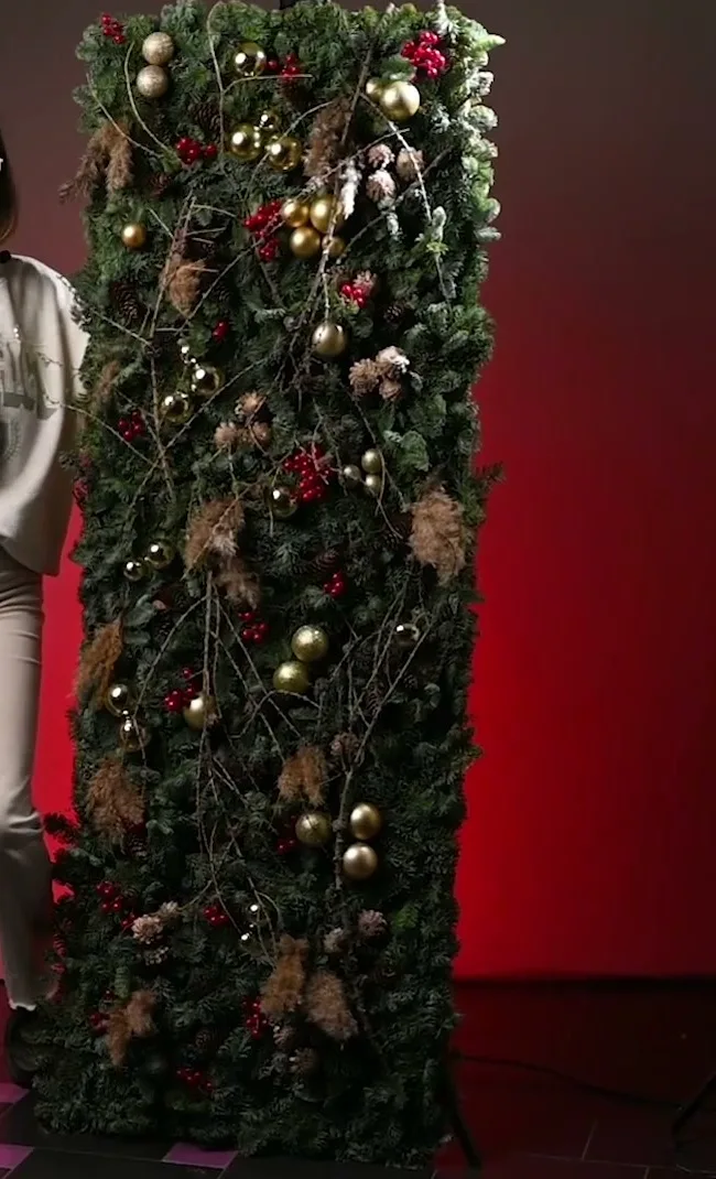 Tall evergreen panel decorated with pinecones, baubles and winding branches.