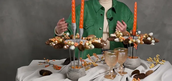 Raised evergreen ring centerpiece with orange candles, gold baubles and pinecones.