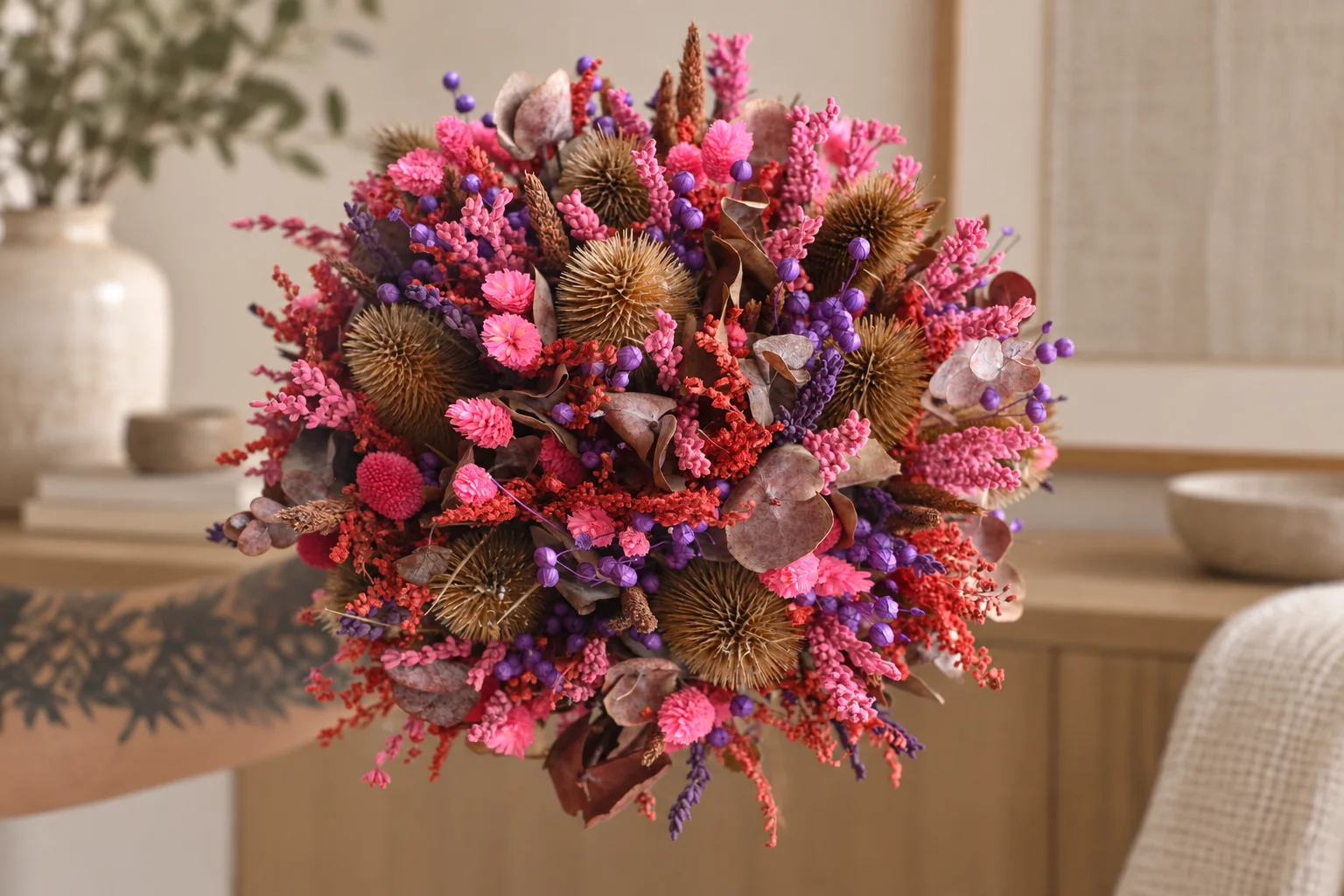 Round pink and purple dried flower bouquet in a styled setting